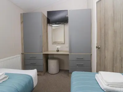 a bedroom with two beds and a desk with a television at The Three Bears Lodge, Coniston Drive 11 in Carnforth