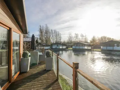 a house with a wooden walkway next to a river at The Three Bears Lodge, Coniston Drive 11 in Carnforth