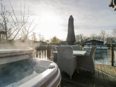 a deck with a table and chairs and an umbrella at The Three Bears Lodge, Coniston Drive 11 in Carnforth