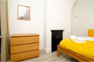 a bedroom with a yellow bed and a dresser at Anfield Haven for 6 in Liverpool