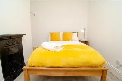 a bedroom with a yellow bed with towels on it at Anfield Haven for 6 in Liverpool