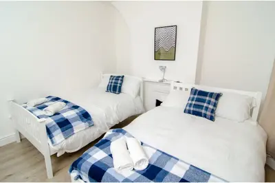 a bedroom with two beds and a chair at Anfield Haven for 6 in Liverpool