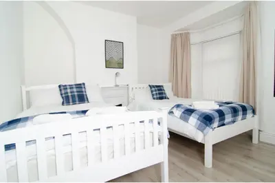 a white bedroom with two beds and a couch at Anfield Haven for 6 in Liverpool