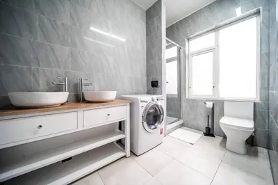 a bathroom with two sinks and a washing machine at Spacious Apartment With A Terrace Style Rooftop in Cleveleys
