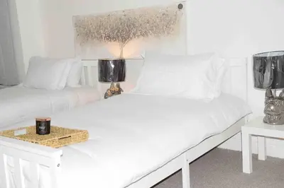 a white bedroom with two beds and a table at Parking Walk to Tower Winter Gardens and Main Attractions in Blackpool