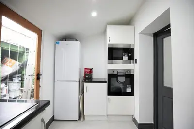 a white kitchen with a refrigerator and a microwave at Dixon House, Sleeps 6, Free Parking, Long or Short Stays - by NMB Property in Horwich