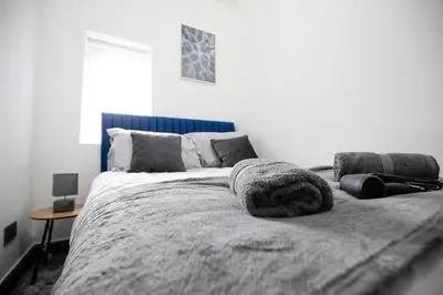 a bedroom with a large bed with a blue headboard at Dixon House, Sleeps 6, Free Parking, Long or Short Stays - by NMB Property in Horwich