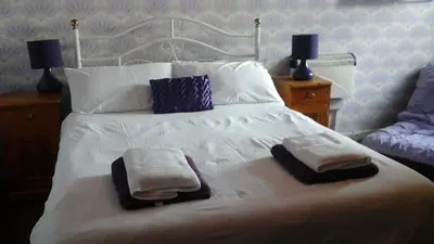 a bedroom with a white bed with towels on it at Shananagens Guesthouse in Blackpool