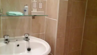 a bathroom with a sink and a glass shelf on the wall at Shananagens Guesthouse in Blackpool