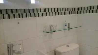 a bathroom with a toilet and a glass shelf on the wall at Shananagens Guesthouse in Blackpool