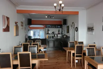 a restaurant with wooden tables and chairs and a bar at Shananagens Guesthouse in Blackpool