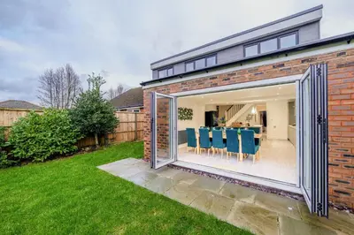 a extension to a brick house with a large sliding glass door at Large 6-Bed house, Free Parking & Motorway Access in Ashton in Makerfield