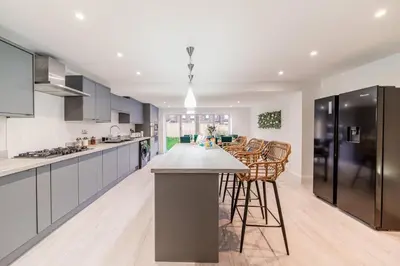 a kitchen with a large island with bar stools at Large 6-Bed house, Free Parking & Motorway Access in Ashton in Makerfield