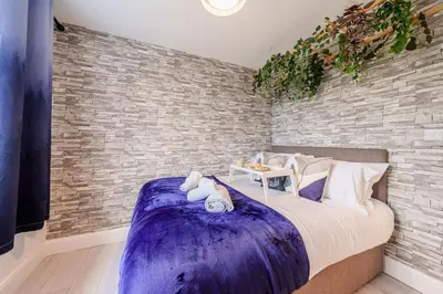 a bedroom with a large bed and a brick wall at Large 6-Bed house, Free Parking & Motorway Access in Ashton in Makerfield