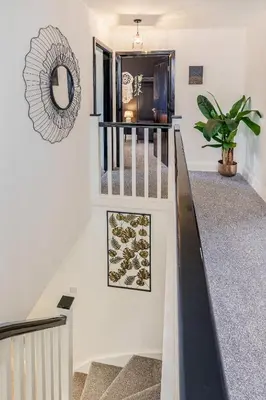 a staircase in a house with a mirror and a plant at Large 6-Bed house, Free Parking & Motorway Access in Ashton in Makerfield