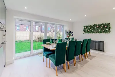 a dining room with a table and green chairs at Large 6-Bed house, Free Parking & Motorway Access in Ashton in Makerfield