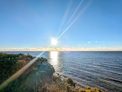 a view of the sun shining over the water at Jenny and Jamie's holiday home on the edge in Morecambe