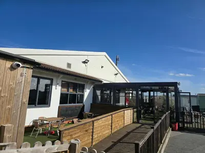 a house with a deck with a table and benches at Jenny and Jamie's holiday home on the edge in Morecambe