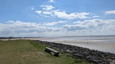 a beach with a rock wall next to the ocean at Jenny and Jamie's holiday home on the edge in Morecambe