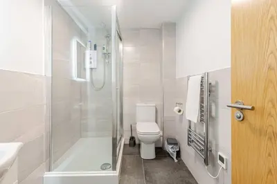a white bathroom with a shower and a toilet at 1-Bed apartment with Sofa Bed right by Liverpool ONE & Concert Square in Liverpool