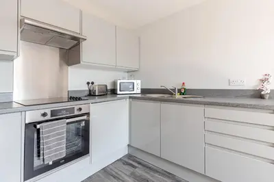 a white kitchen with white cabinets and a microwave at 1-Bed apartment with Sofa Bed right by Liverpool ONE & Concert Square in Liverpool