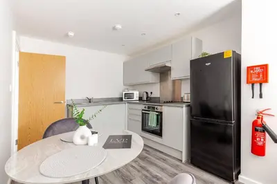 a kitchen with a table and a black refrigerator at 1-Bed Apartment With Sofa Bed in City Centre, Steps from Bold Street and Nightlife in Liverpool