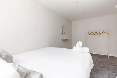 a white bedroom with a white bed with a towel on it at 1-Bed Apartment With Sofa Bed in City Centre, Steps from Bold Street and Nightlife in Liverpool