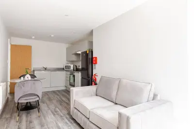 a living room with a white couch and a kitchen at 1-Bed Apartment With Sofa Bed in City Centre, Steps from Bold Street and Nightlife in Liverpool