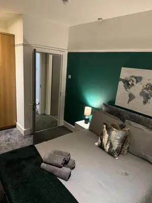 a bedroom with a large bed with a green wall at Cherry Loft in Liverpool