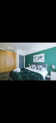 a bedroom with a large bed with a green wall at Cherry Loft in Liverpool