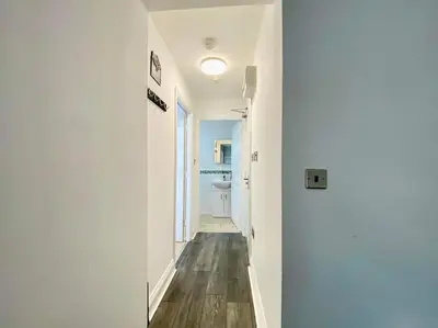 a hallway with white walls and wood floors and a sink at JMC's Place in Blackpool