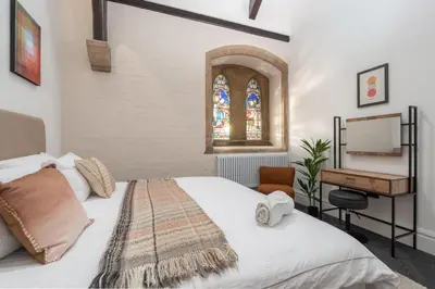 a bedroom with a bed with a desk and a window at The Spire! Historic Features Rare 1800s Church in Waterloo
