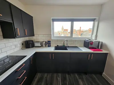 a kitchen with black cabinets and a sink and a window at Market Quarter, town centre, free parking and wifi in Southport