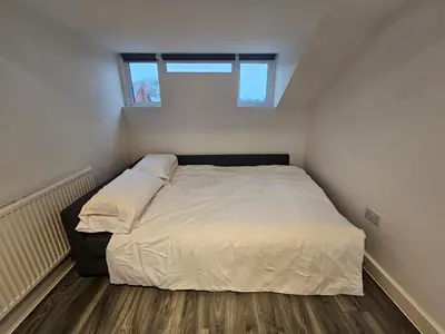 a bedroom with a bed with white sheets and a window at Market Quarter, town centre, free parking and wifi in Southport