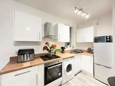 a kitchen with white cabinets and a washer and dryer at City Link Apartments Perfect Stay for Concert Goers, Football Fans and Contractors, Closer to Liverpool City Centre, Everton, Liverpool Grounds in Liverpool
