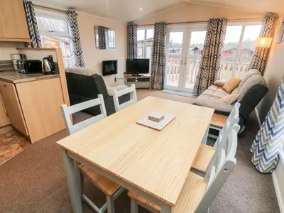 a living room with a dining room table and a kitchen at 6 Sherwood in Carnforth