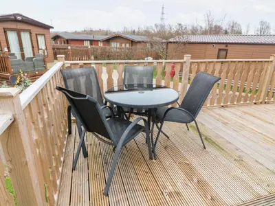 a table and two chairs on a wooden deck at 6 Sherwood in Carnforth