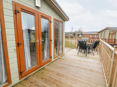 a deck with glass doors and a table and chairs at 6 Sherwood in Carnforth