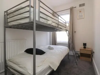 a bedroom with a bunk bed with white sheets at 21 Eaves Street in Blackpool