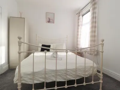a white bed in a bedroom with a window at 21 Eaves Street in Blackpool
