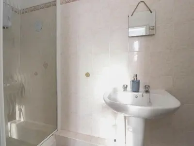 a white bathroom with a sink and a shower at 21 Eaves Street in Blackpool