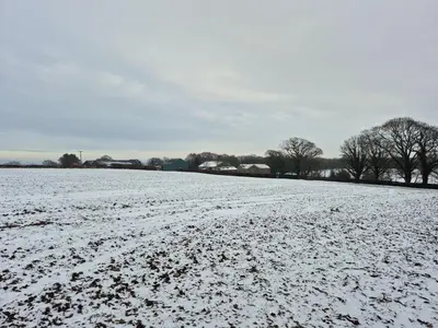 a snow covered field with trees in the background at The Retreat in Eccleston