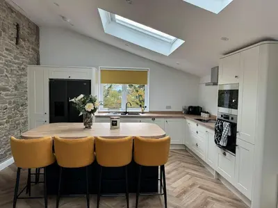 a kitchen with a wooden table and yellow chairs at The Retreat in Eccleston