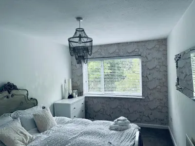 a bedroom with a bed and a window and a chandelier at House - Sleeps 6 Hot-tub & Free Parking in Skelmersdale