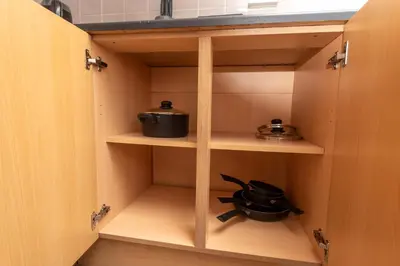 a cupboard with two pans and a pot at Modern 3 bed, sleeps 8 in Saint Helens