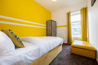 a yellow bedroom with a bed and a window at Family Stay on Barnes Street in Clayton le Moors