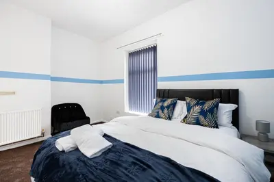 a bedroom with a large bed and a chair at Family Stay on Barnes Street in Clayton le Moors