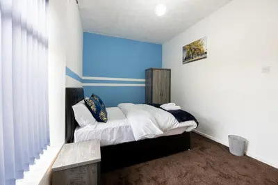 a bedroom with a bed with a blue wall at Family Stay on Barnes Street in Clayton le Moors
