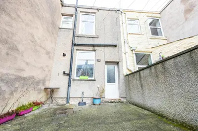a building with a white door next to a wall at Family Stay on Barnes Street in Clayton le Moors