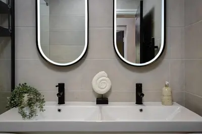 a bathroom sink with two mirrors and a shell on it at The Shoreline Collection by STAMP in Blackpool